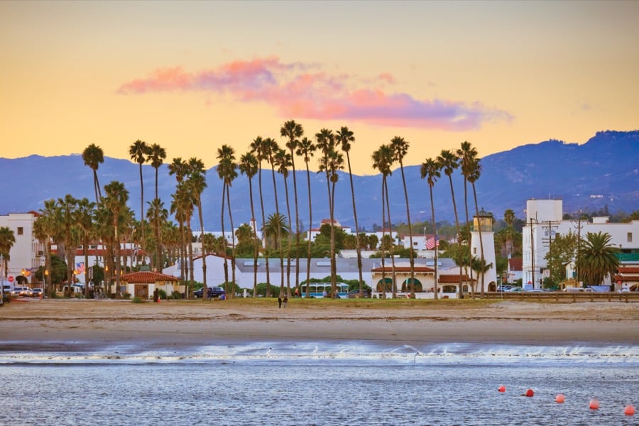 Palm trees along a Southern California beach at sunrise, with hills behind.