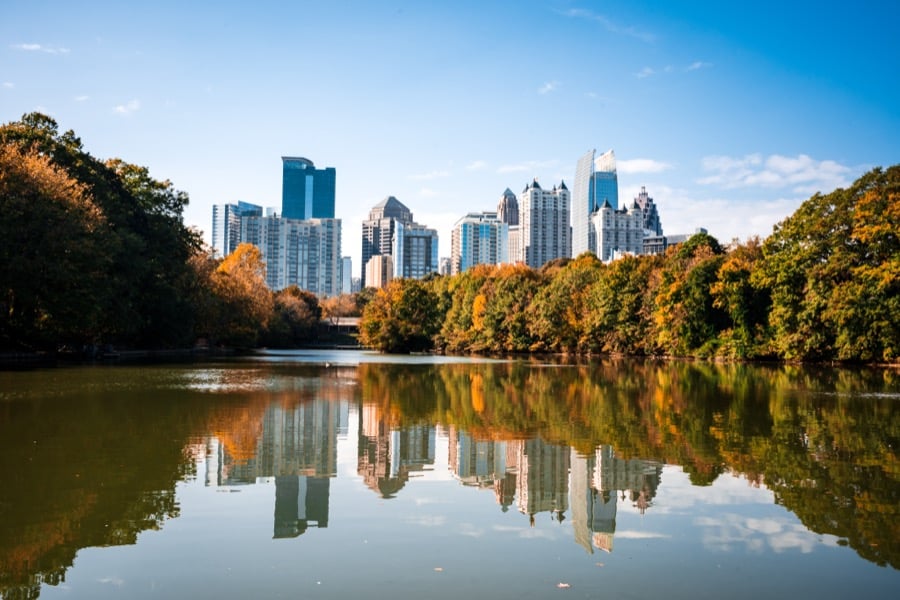 The Atlanta skyline behind a lake fringed with autumn trees.