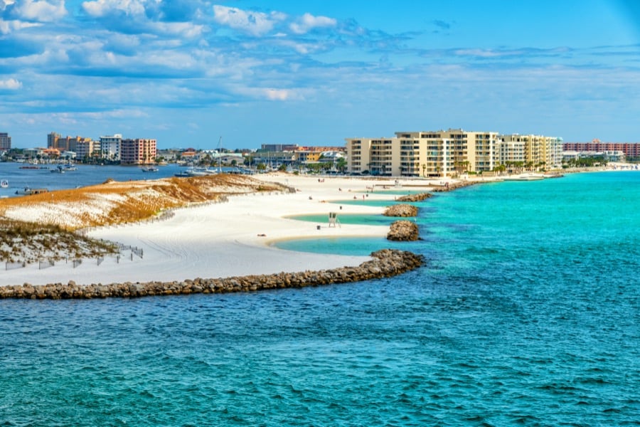 Turquoise water meeting white sand beside the beachfront buildings at Destin.